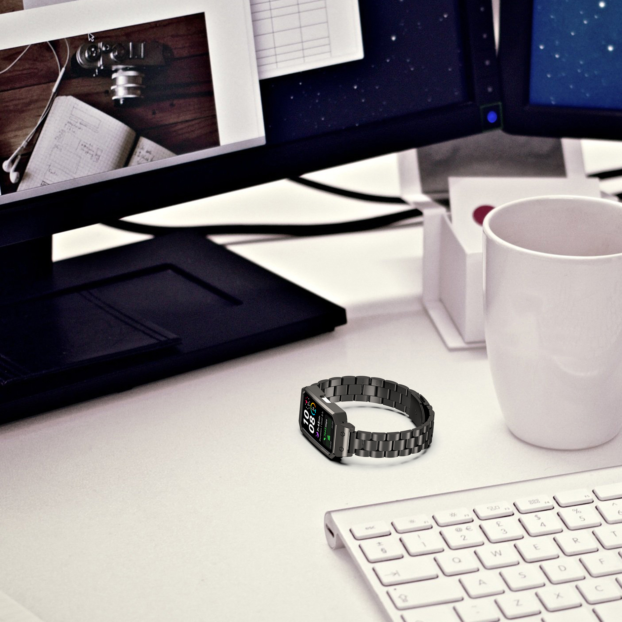 Armbanduhr auf einem Schreibtisch. Tastatur, Monitore und eine Tasse. Weiße Oberfläche. Nahaufnahme, Büroumgebung.