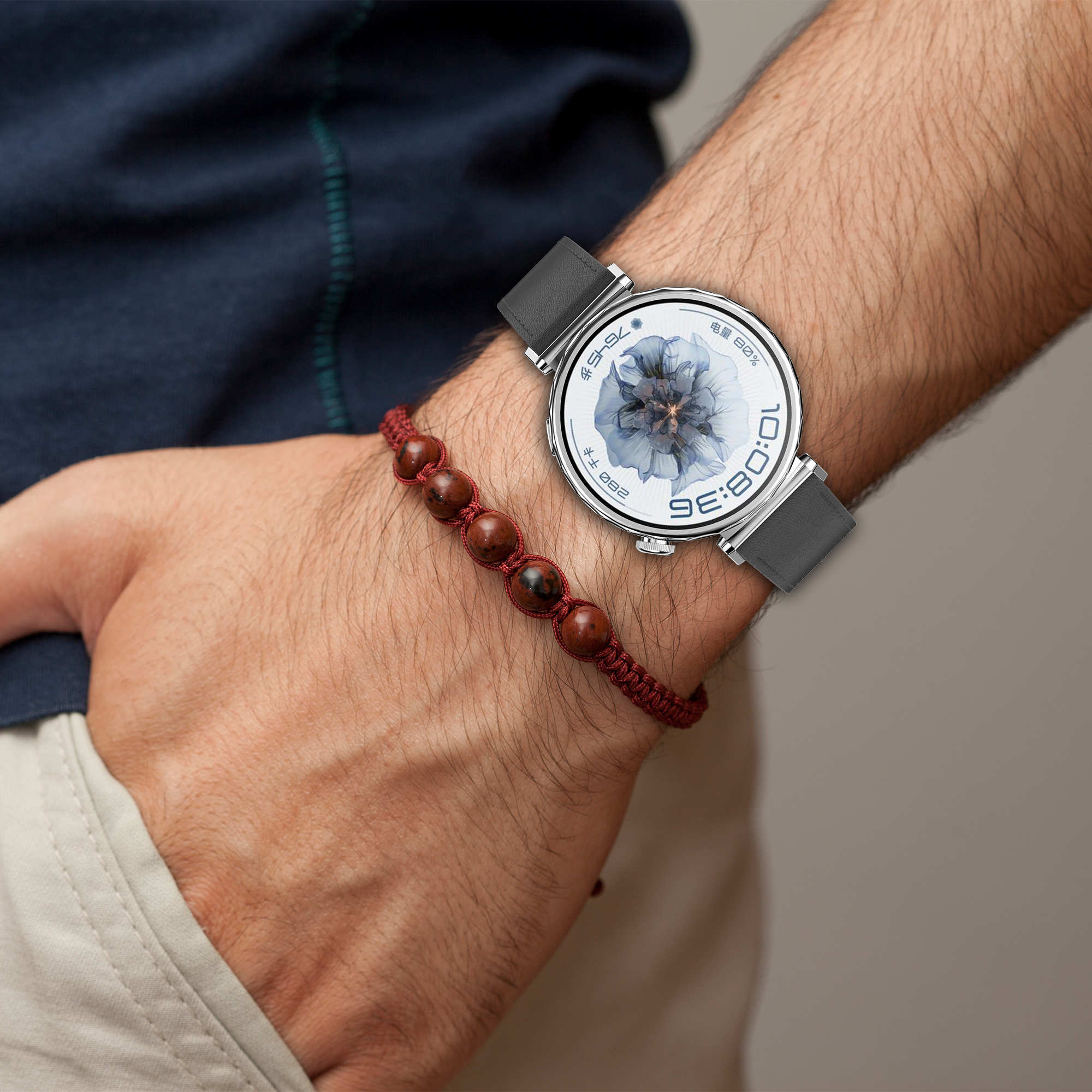 Il polso di una persona con un orologio e un braccialetto di perline rosse.