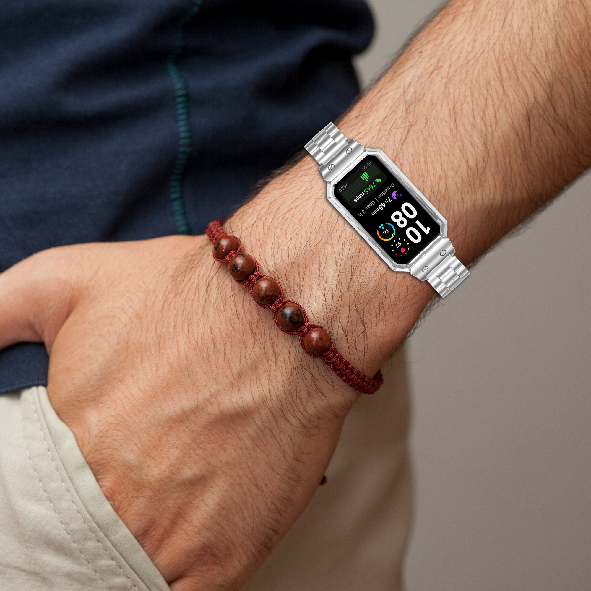 Das Handgelenk einer Person mit einer silbernen Smartwatch und einem roten Perlenarmband.