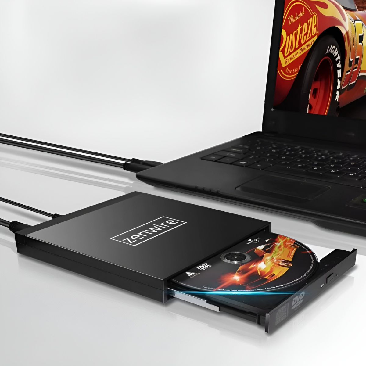 Czarny napęd DVD podłączony do laptopa. Laptop pokazuje film o samochodach, a napęd DVD jest otwarty.