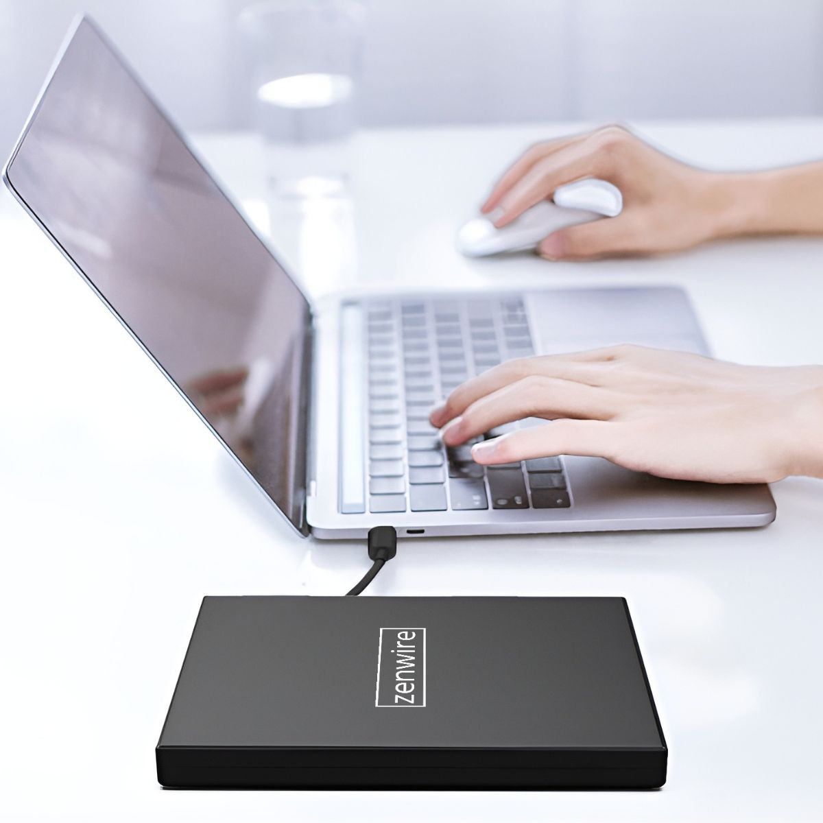 Dłonie używają laptopa i myszy z napędem DVD. Napęd DVD ma logo zenwire.