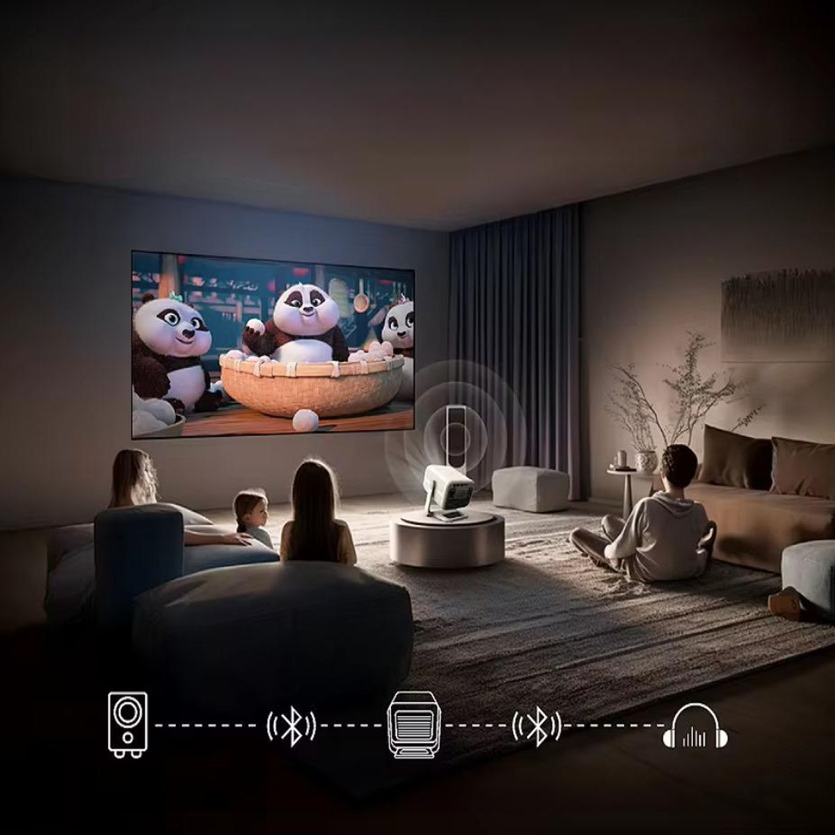 Ludzie oglądają film wyświetlany na ścianie. Pokazano projektor i urządzenia dźwiękowe.