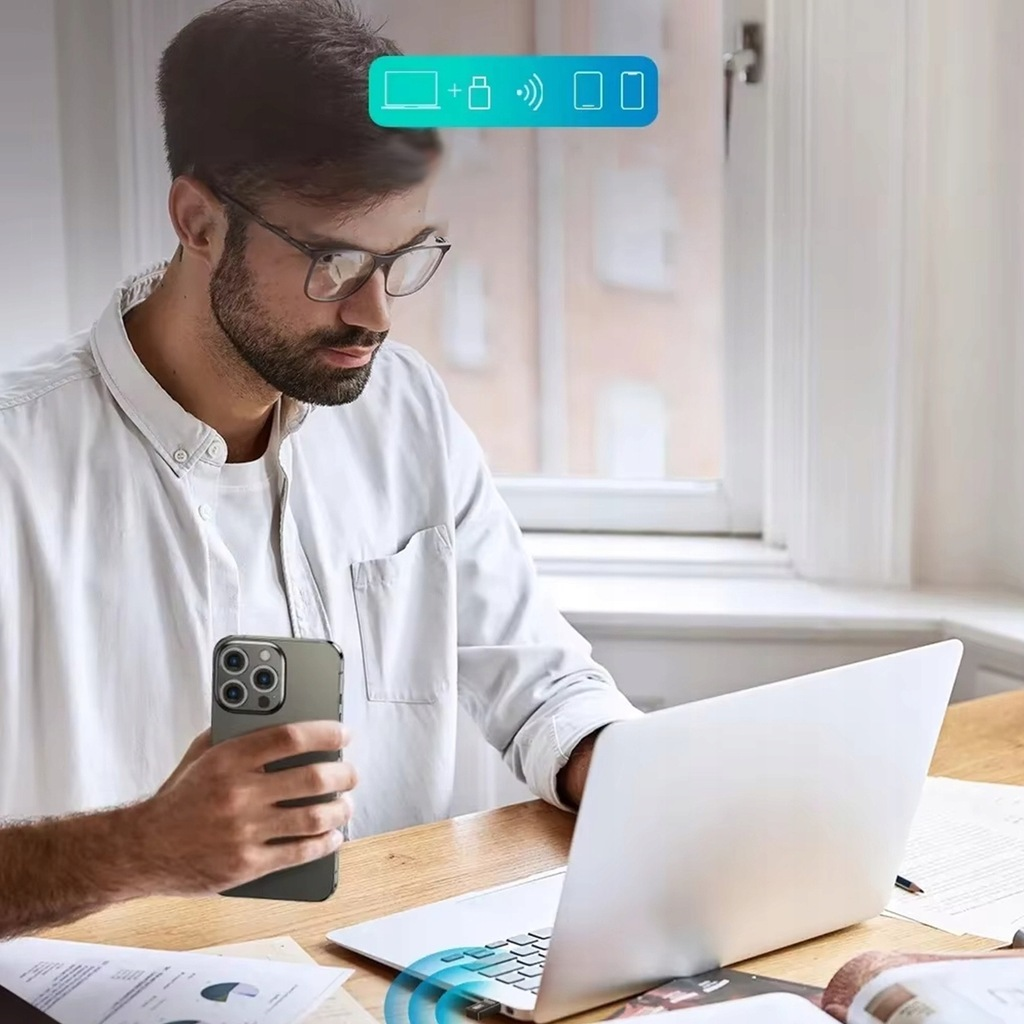 Osoba korzystająca z laptopa i telefonu. Telefon jest połączony z laptopem za pośrednictwem połączenia.