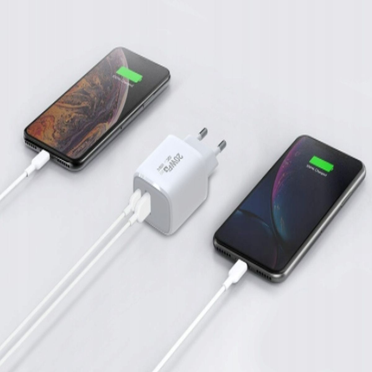 Dwa smartfony ładujące się z białą ładowarką. Jeden telefon się ładuje, drugi jest w pełni naładowany.