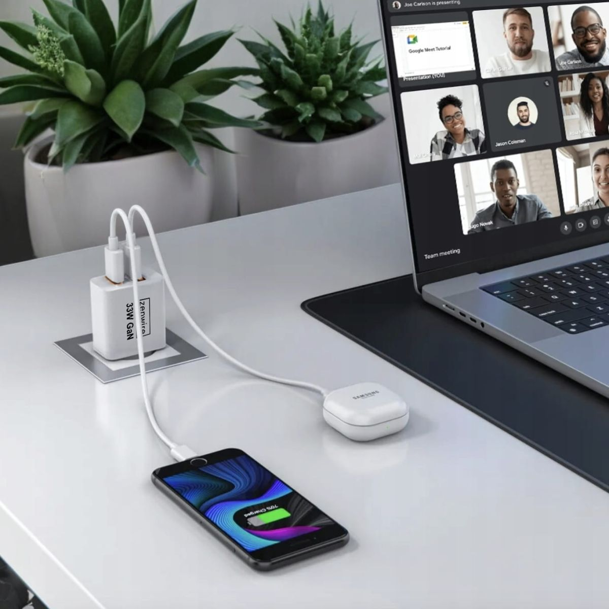 Telefon ładujący się, podłączony do ładowarki z etykietą "zenwire", obok laptopa z rozmową wideo.
