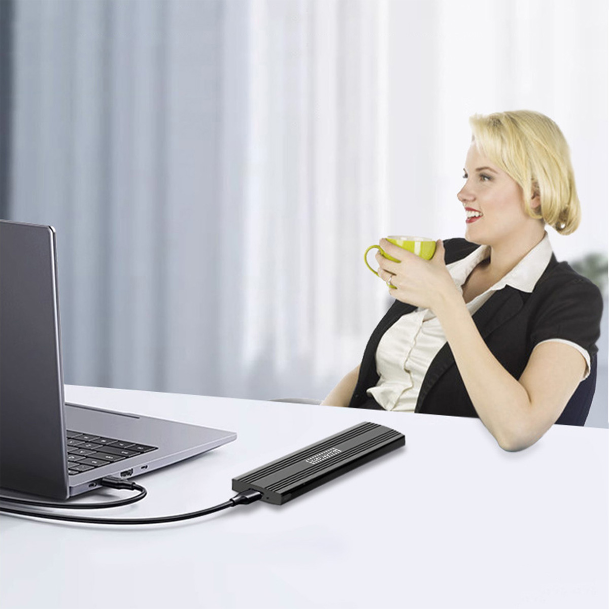 Kobieta z kubkiem patrzy na laptopa. Czarne urządzenie "zenwire" leży obok laptopa z podłączonym kablem.