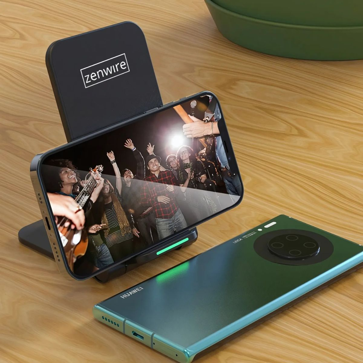 Telefon ładujący się na stojaku Zenwire, pokazujący grupę ludzi. W pobliżu drugi telefon.