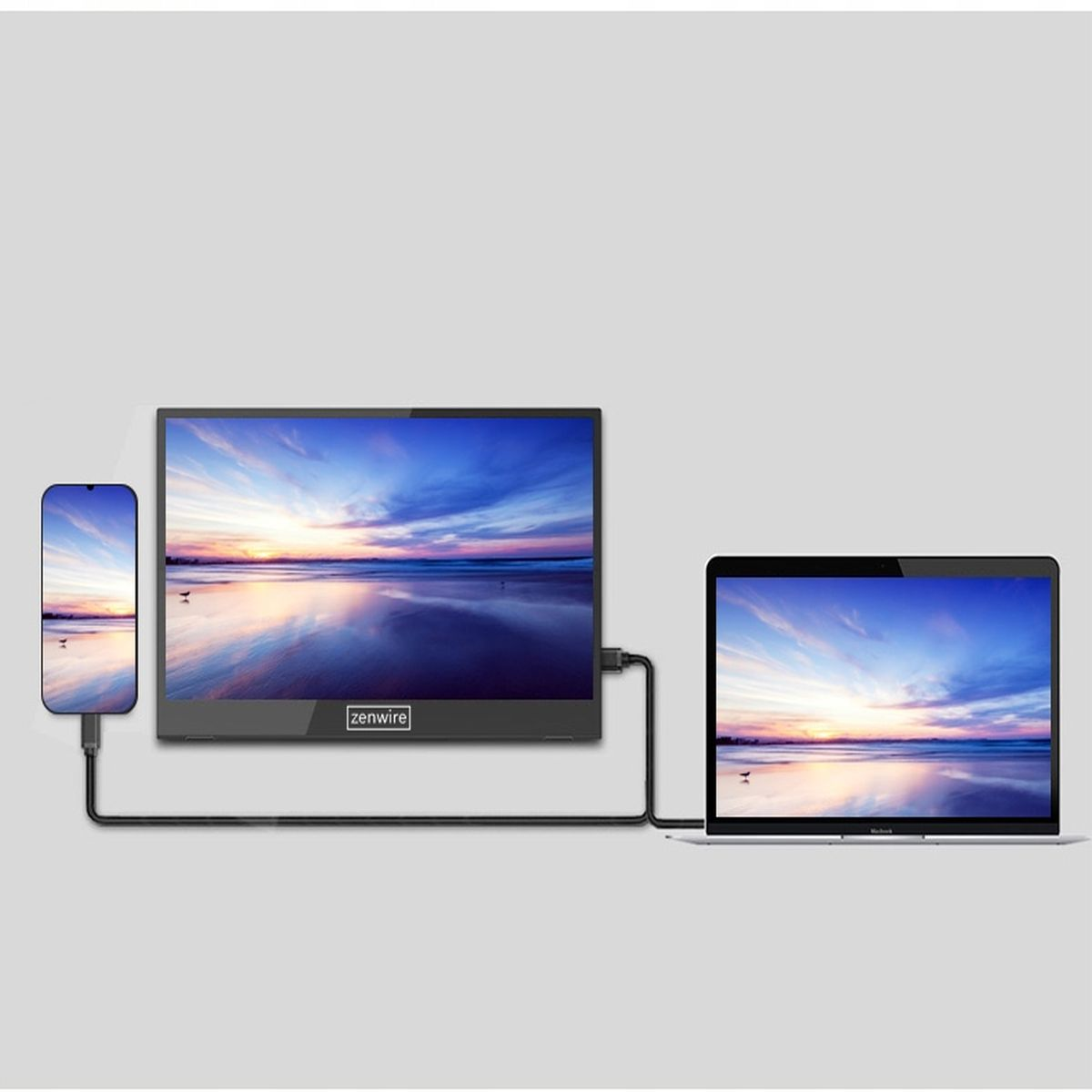 Telefon i laptop podłączone do monitora za pomocą kabli. Monitor wyświetla scenę zachodu słońca.