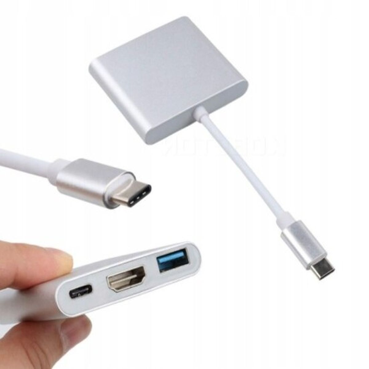 Srebrny adapter z portami USB-C i USB. Ręka trzyma adapter. Podłączone kable.