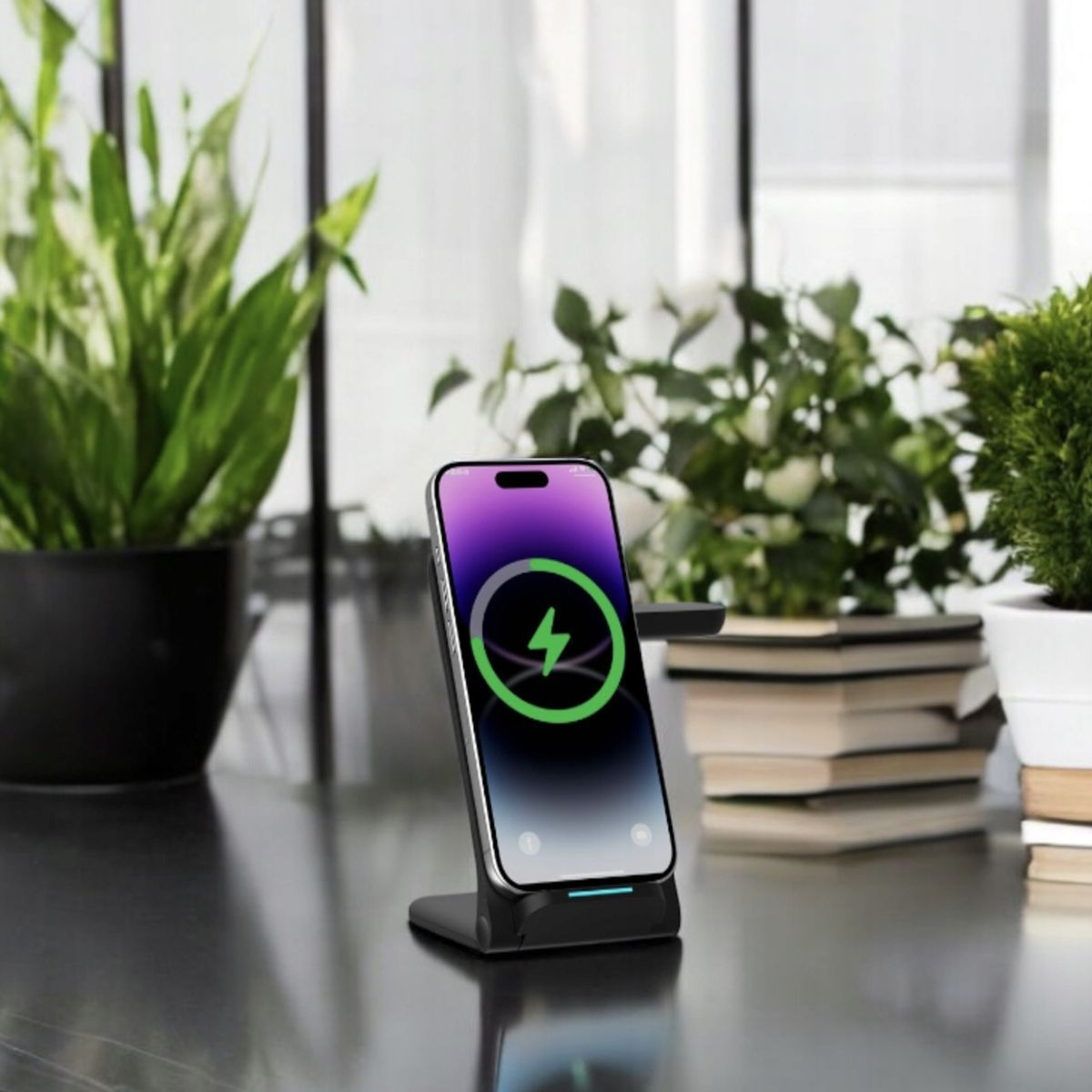 Stacja ładująca z telefonem wyświetlającym ikonę ładowania. Rośliny i książki w tle.