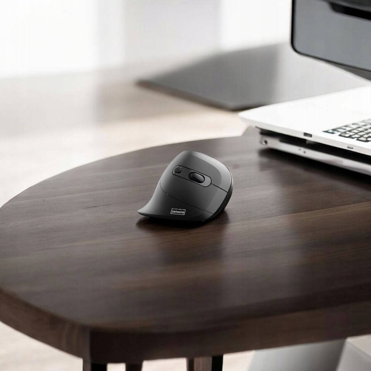 Czarna ergonomiczna mysz na drewnianym stole. Laptop w tle.