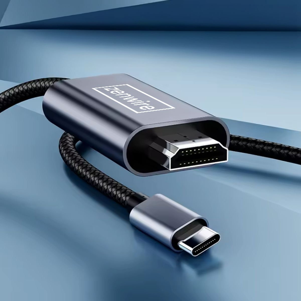 Kabel USB-C do HDMI na niebieskiej powierzchni. Szare złącza i czarny pleciony kabel.