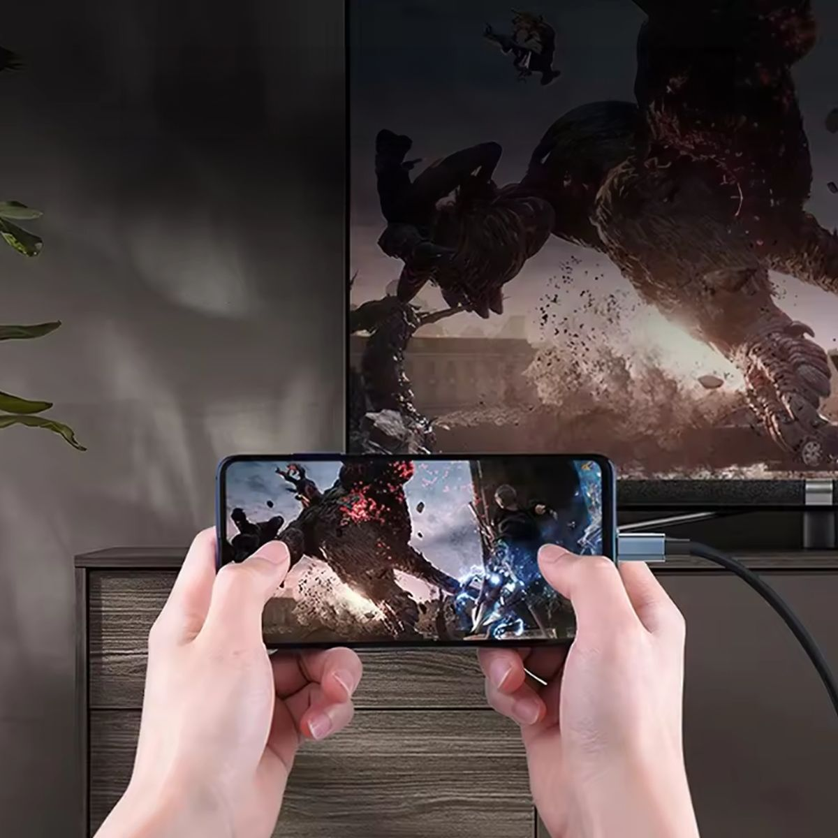 Dłonie trzymające telefon podłączony do telewizora. Telefon wyświetla grę wideo.