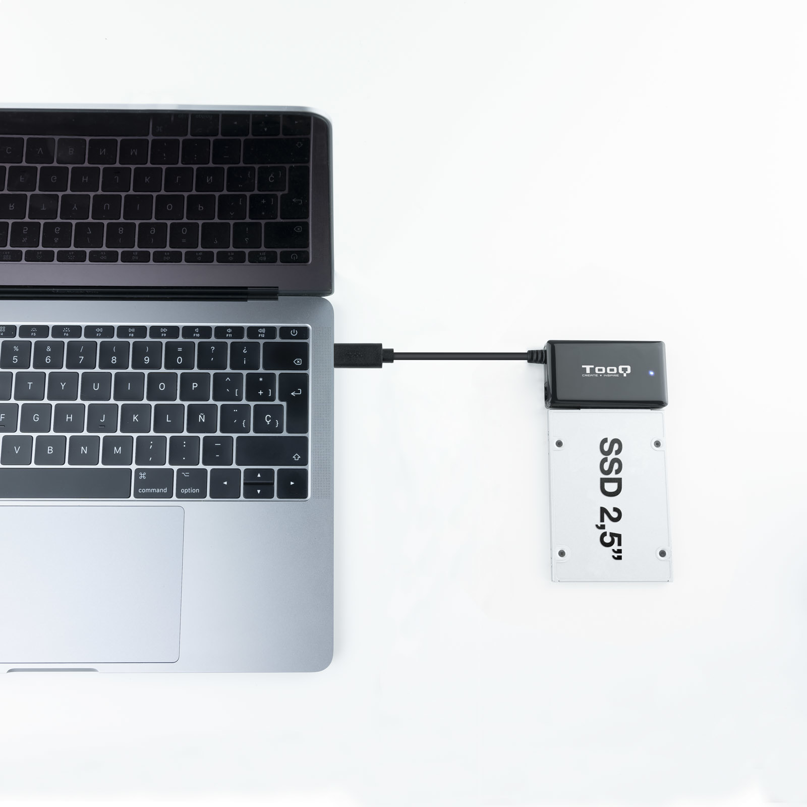 Laptop collegato a un SSD nero da 2,5”. L'SSD è posizionato sul tavolo bianco.