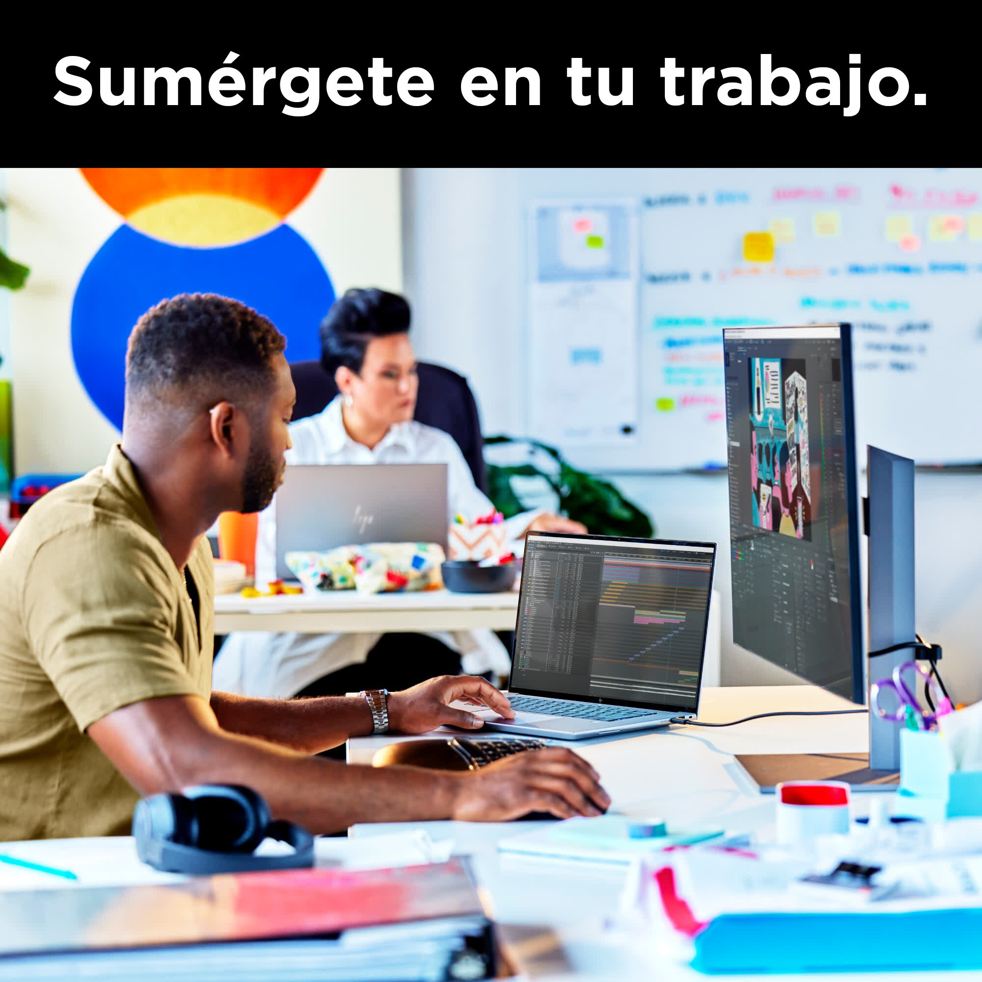 Hombre y mujer trabajando en escritorios con computadoras. Pizarra de fondo. Texto: 'Sumérgete en tu trabajo'.