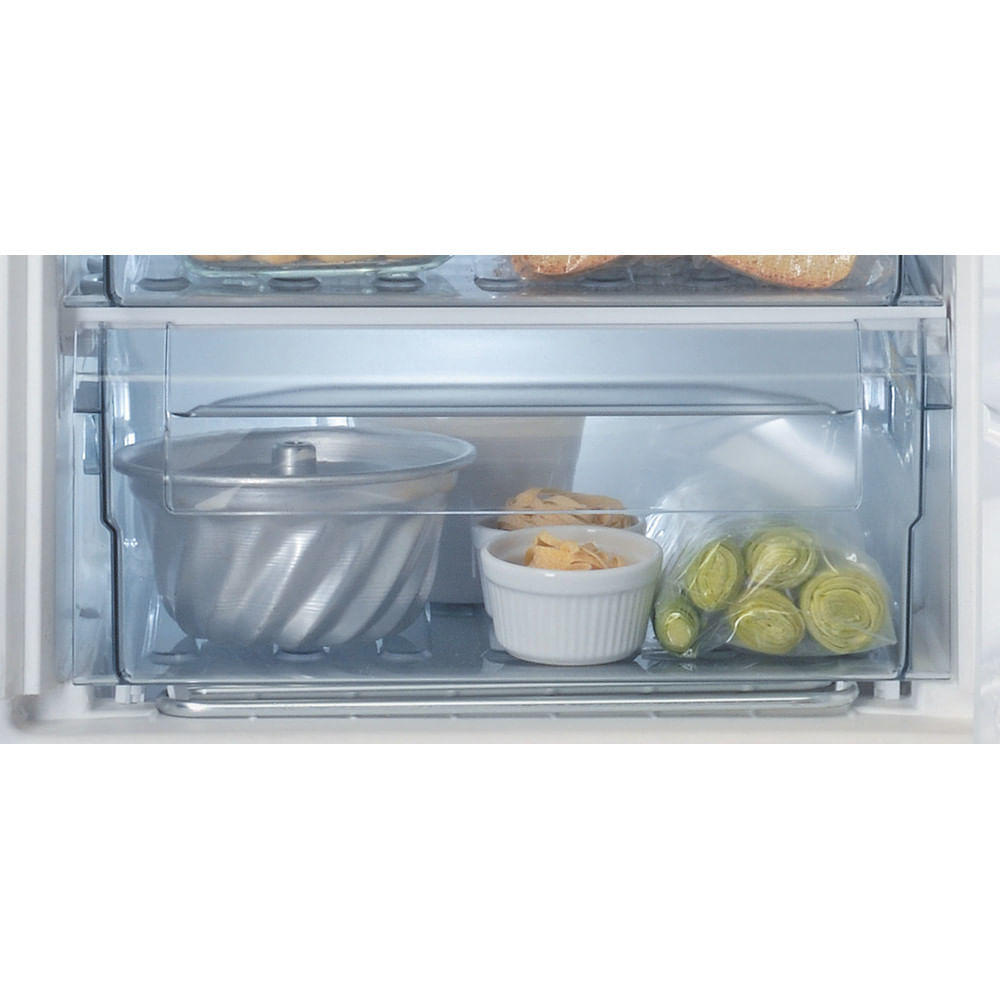 Cassetto del frigorifero con alimenti all'interno. Pentola in metallo, ciotole bianche e carciofi confezionati.