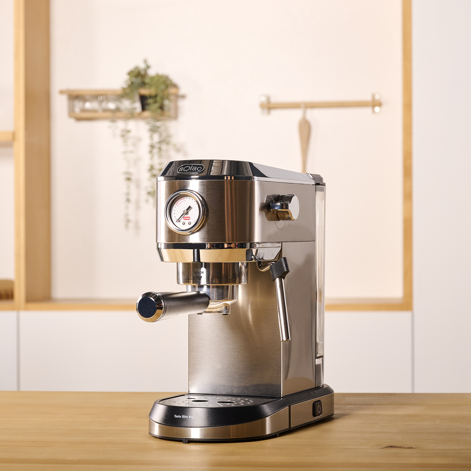 Máquina de espresso de acero inoxidable sobre mesa de madera, con fondo de cocina.