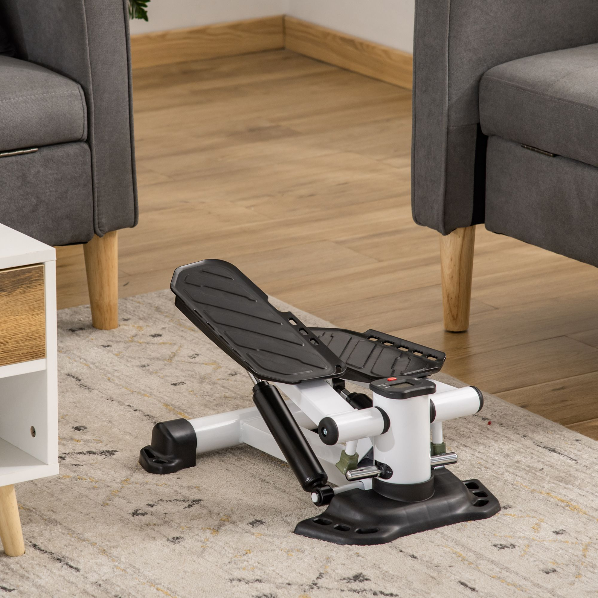 Ein Heim-Stepper auf einem Teppich, im Hintergrund zwei graue Sessel.