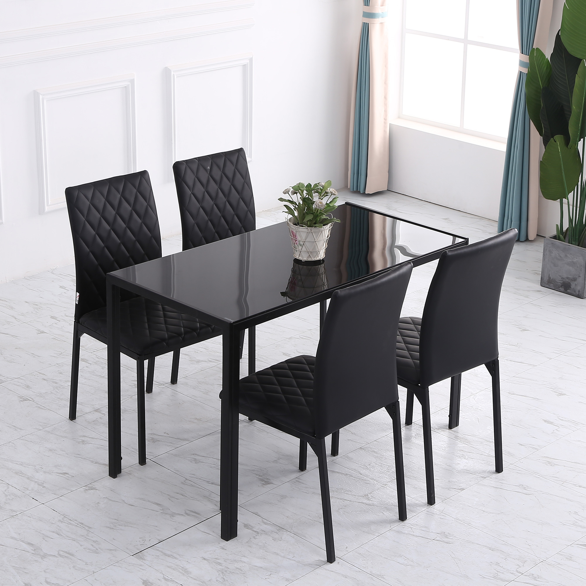 Un tavolo da pranzo in vetro nero con quattro sedie nere con sedute a rombi.