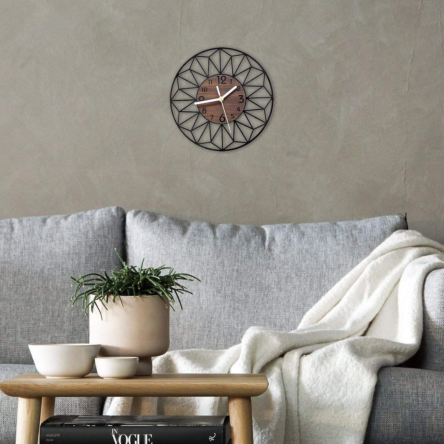 Moderne Uhr mit geometrischem Design an einer Wand über Sofa und Tisch.