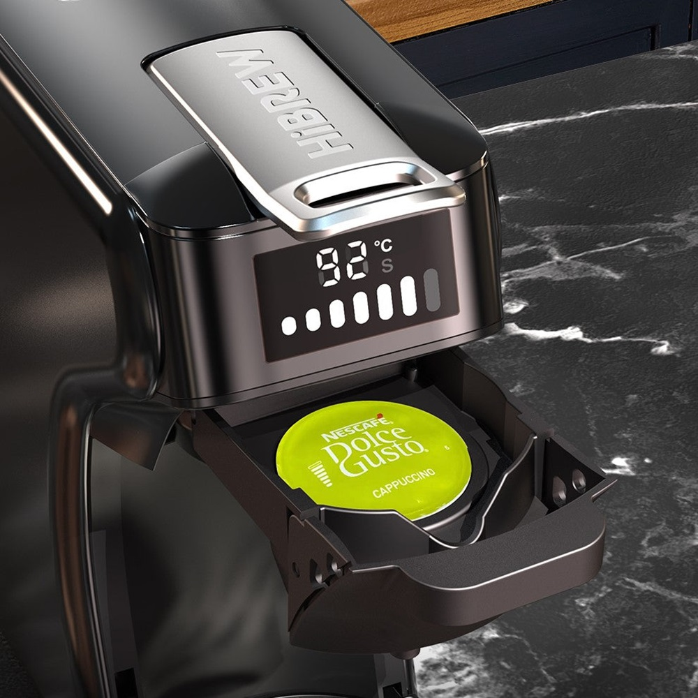Nahaufnahme einer schwarzen Kaffeemaschine. Eine grüne Dolce Gusto Kapsel liegt im offenen Fach.