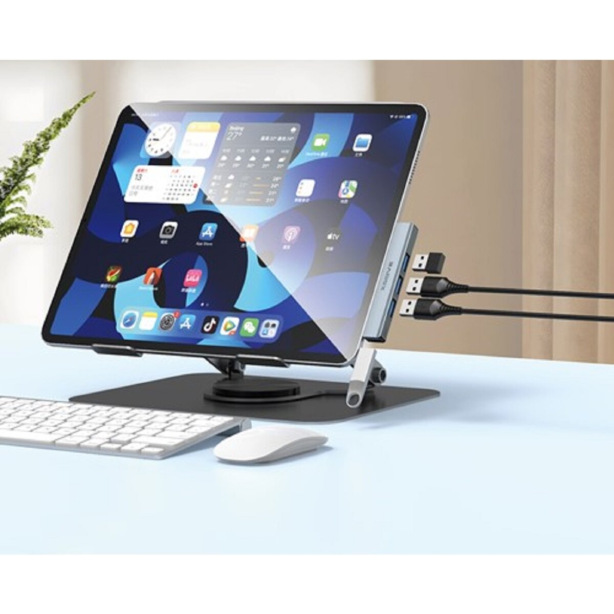 Ein iPad ist mit einem Ständer mit USB-Anschlüssen verbunden. Eine Tastatur und Maus liegen auf dem Schreibtisch. Der Bildschirm ist an.