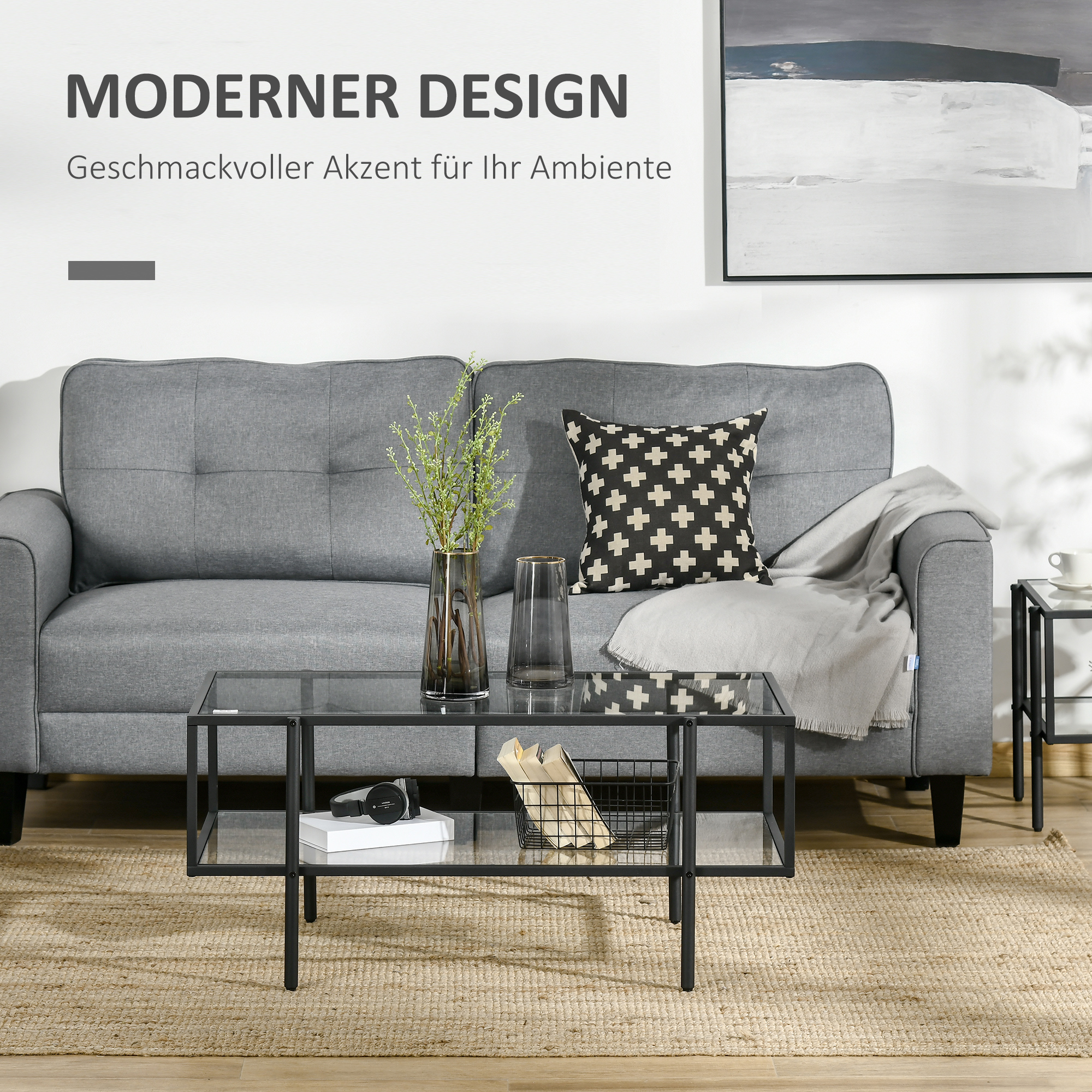 Ein modernes Wohnzimmer mit grauem Sofa, Glastisch und Teppich.