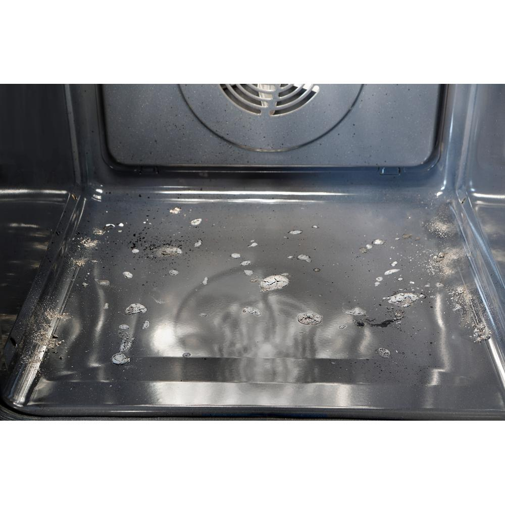 Interior de un horno sucio. Se ve un ventilador y manchas en el fondo.