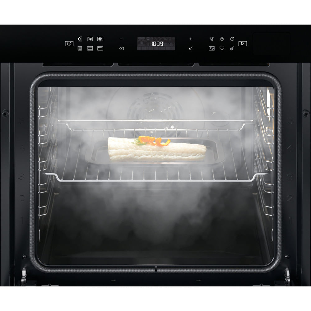 Un interno forno con un vassoio che contiene cibo, vapore visibile.