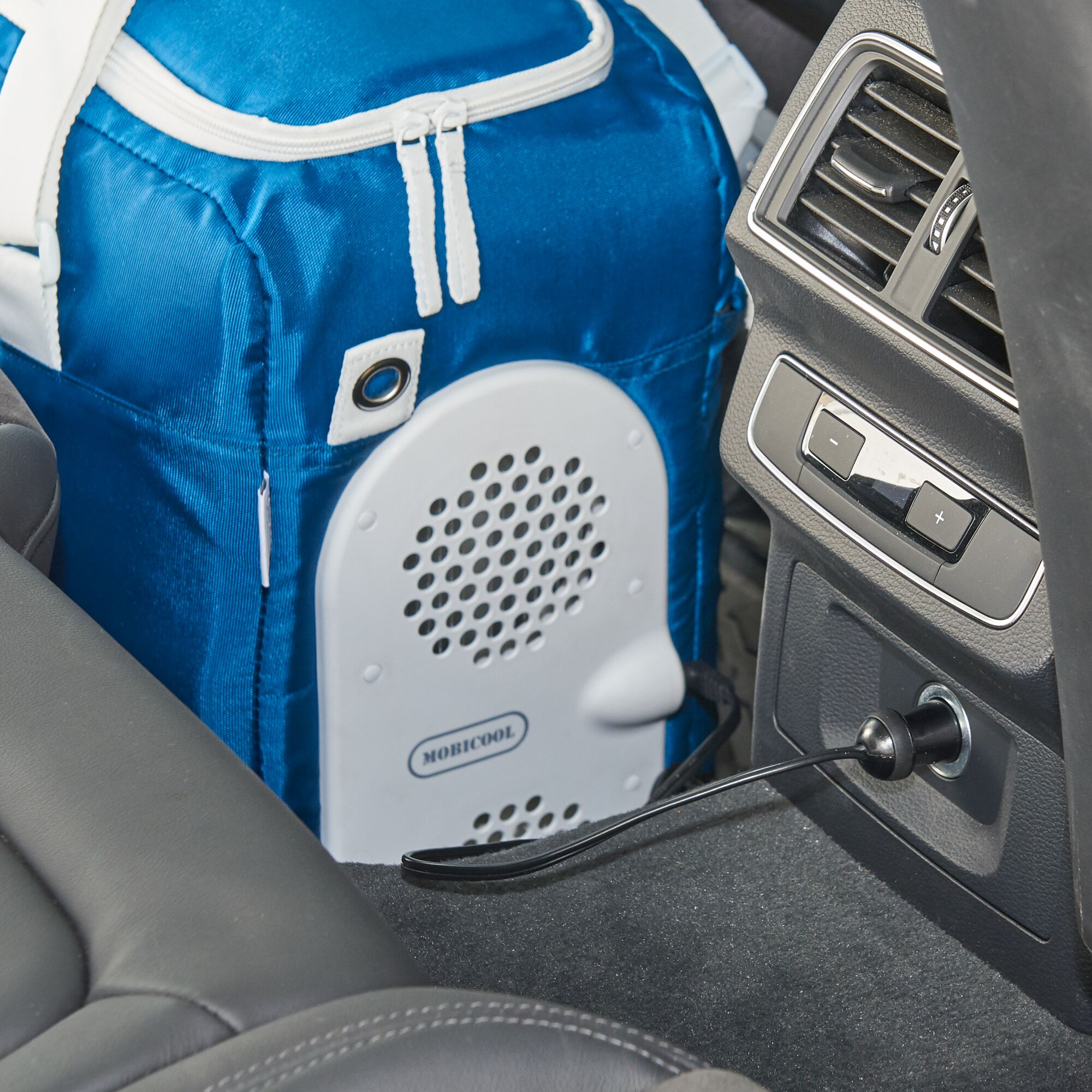 Niebieska torba chłodząca, biały głośnik i czarny kabel w samochodzie.