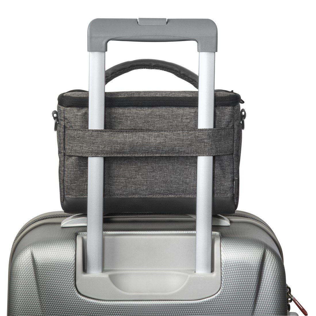 Szara torba na aparat znajduje się na srebrnej walizce z uchwytem.