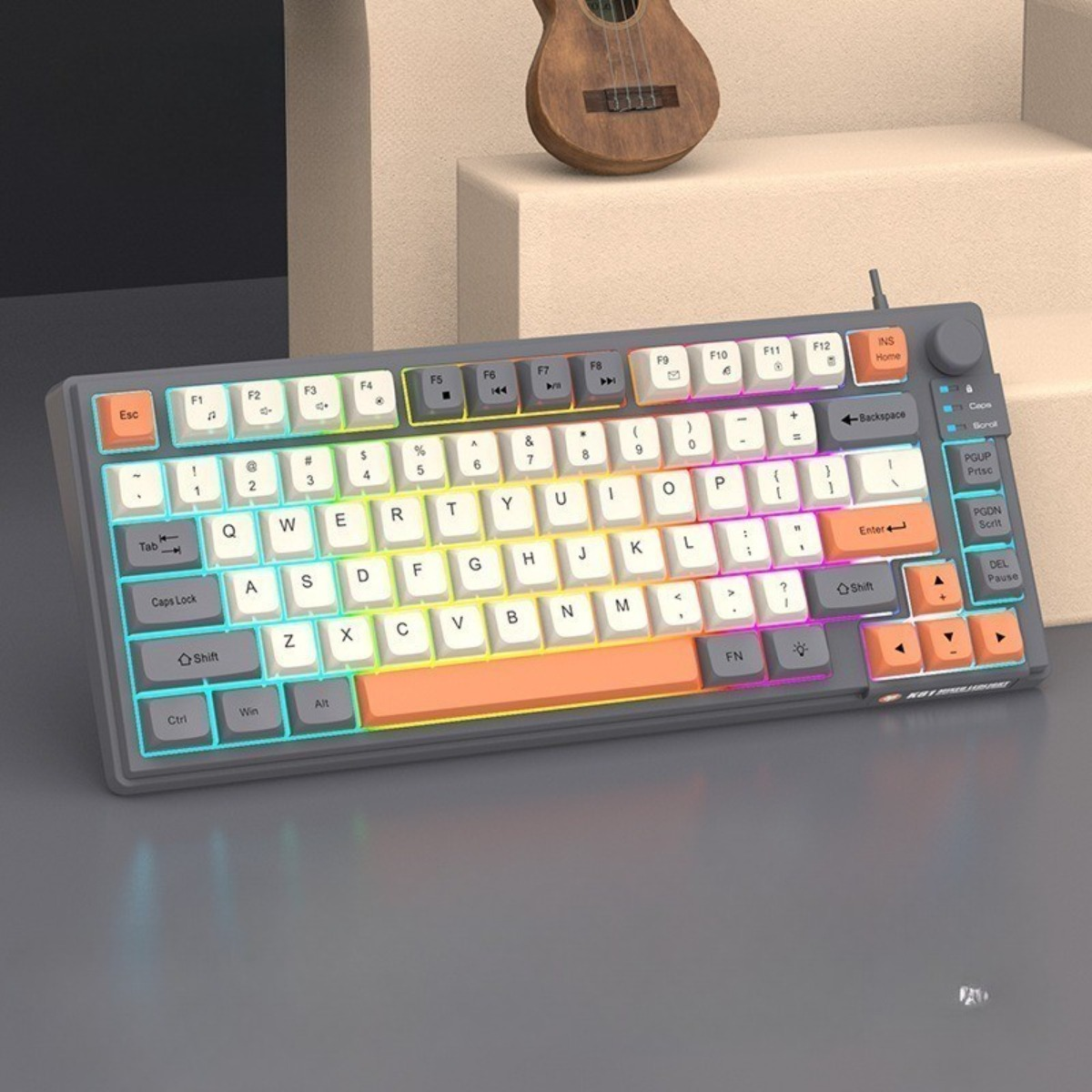 Eine graue Tastatur mit farbcodierten Tasten und einem Farbverlauf-Regenbogeneffekt, eine kleine Holzgitarre im Hintergrund.