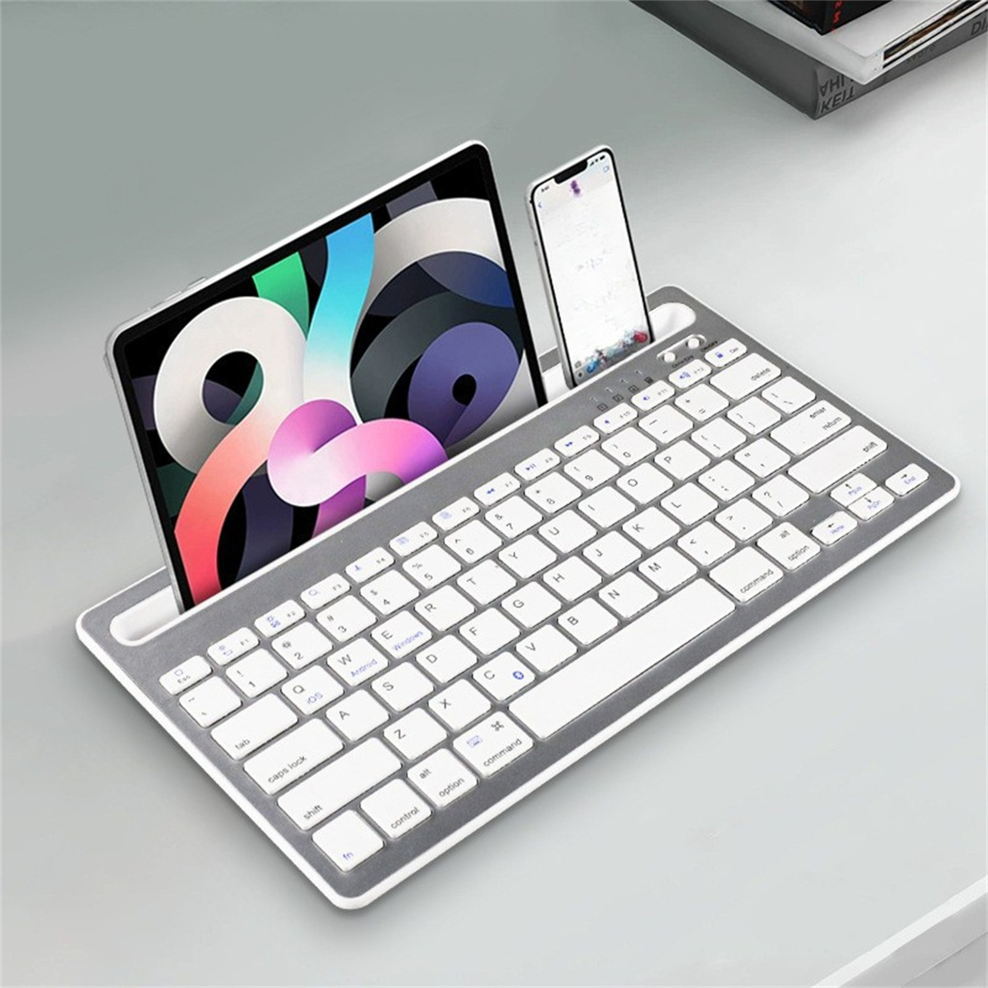 Tastatur mit Tablet und Telefon. Es hat einen weißen Rahmen. Tablet hinten, Telefon rechts.
