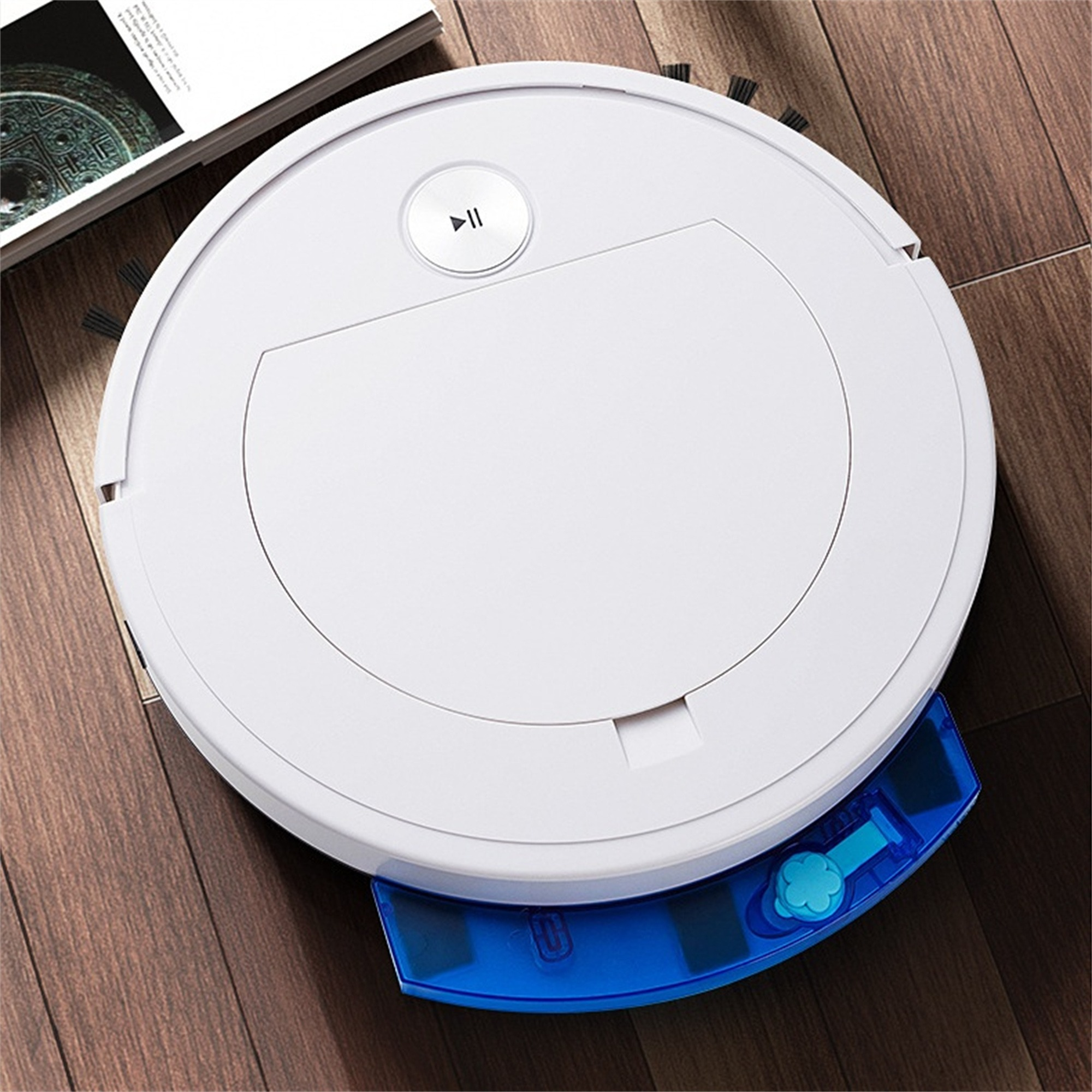 Ein weißer Roboter-Staubsauger auf einem Holzboden. Der Staubsauger ist rund mit einem blauen Wassertank.