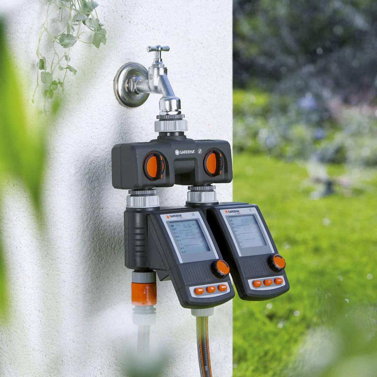 Garten-Bewässerungsuhr an einer Wand installiert. Sie ist an einen Wasserhahn angeschlossen und hat ein Digitaldisplay.