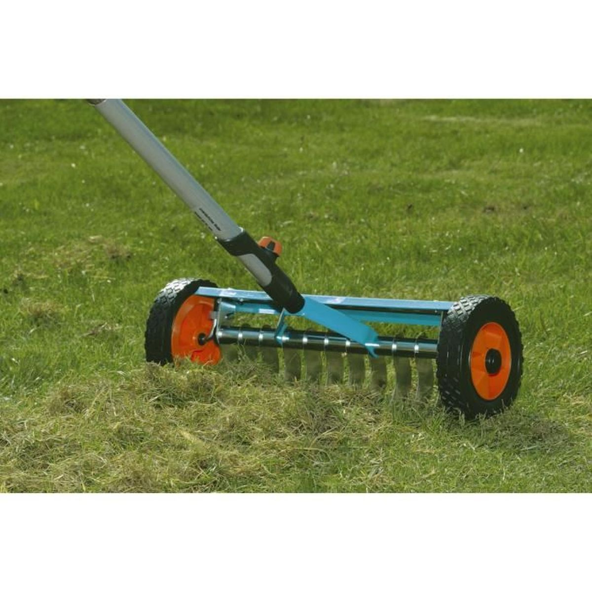 A green lawn with a blue and gray lawn rake. The rake has black tires and orange centers.