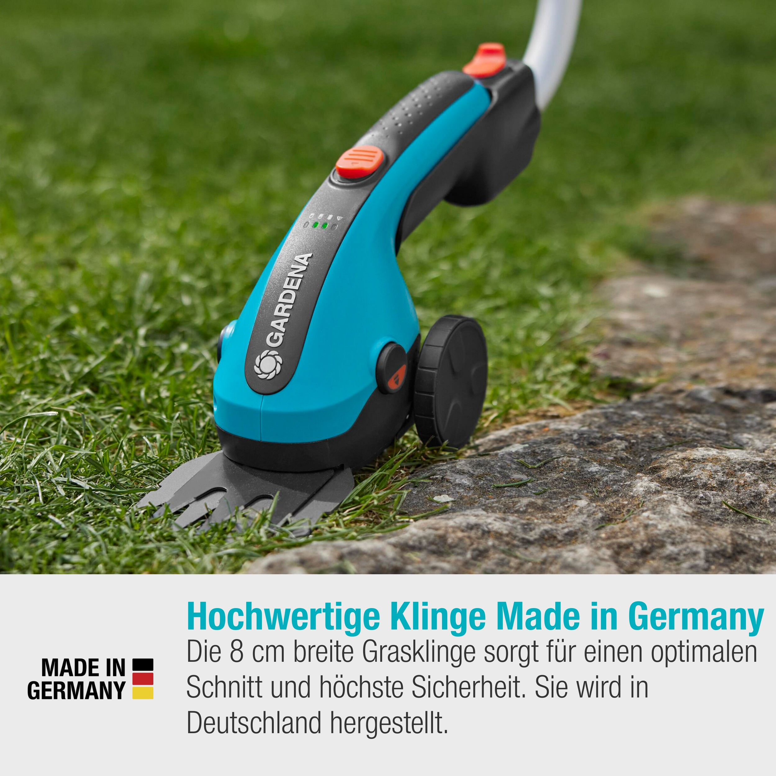Niebiesko-czarna podkaszarka do trawy GARDENA na zielonej trawie. Czerwony przycisk. Tekst: 'Hochwertige Klinge Made in Germany'.