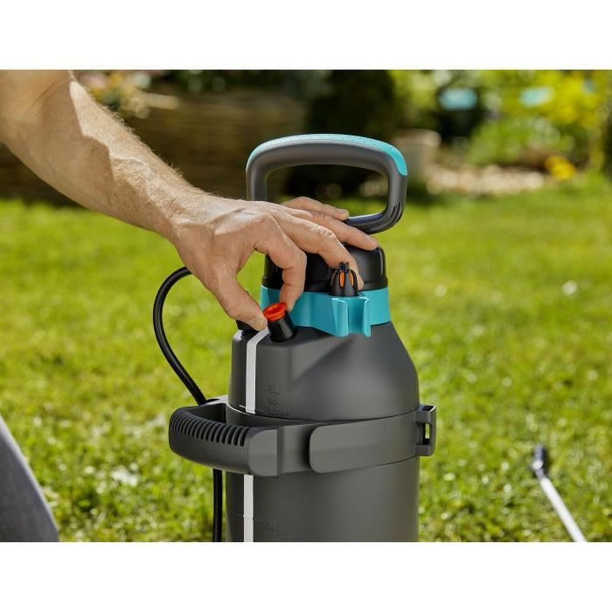 Die Hand einer Person bedient einen Gartensprüher.