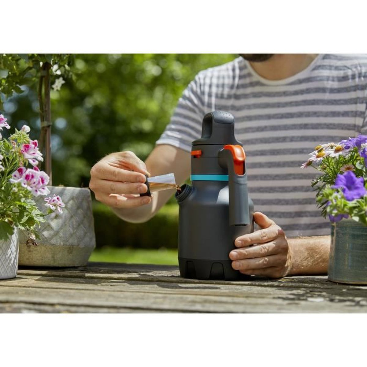 Person gießt Flüssigkeit aus einer Flasche in einen Behälter im Freien.