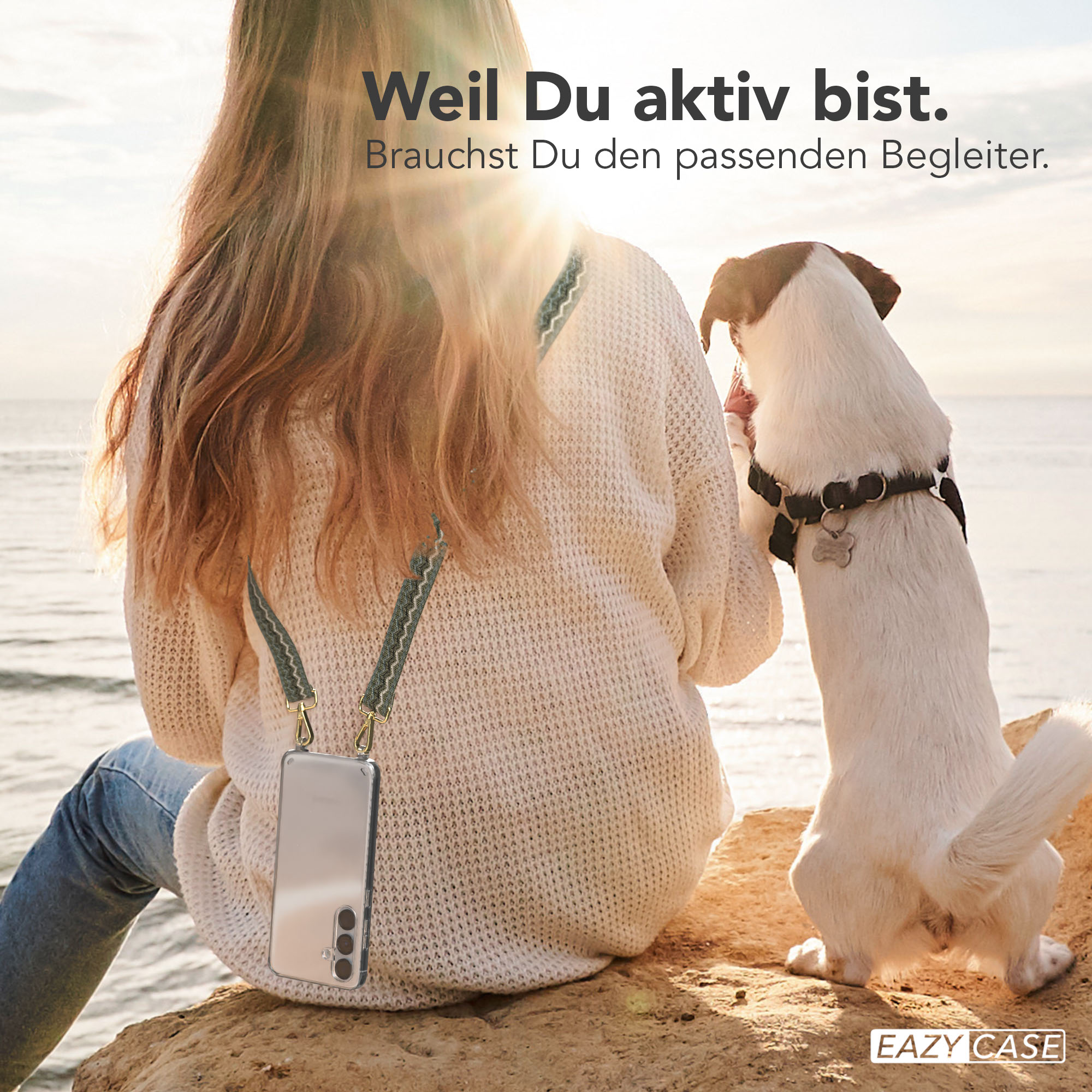 Eine Frau sitzt auf einem Felsen mit einem Telefon in einer Hülle. Ein Hund steht neben ihr und schaut auf das Telefon.