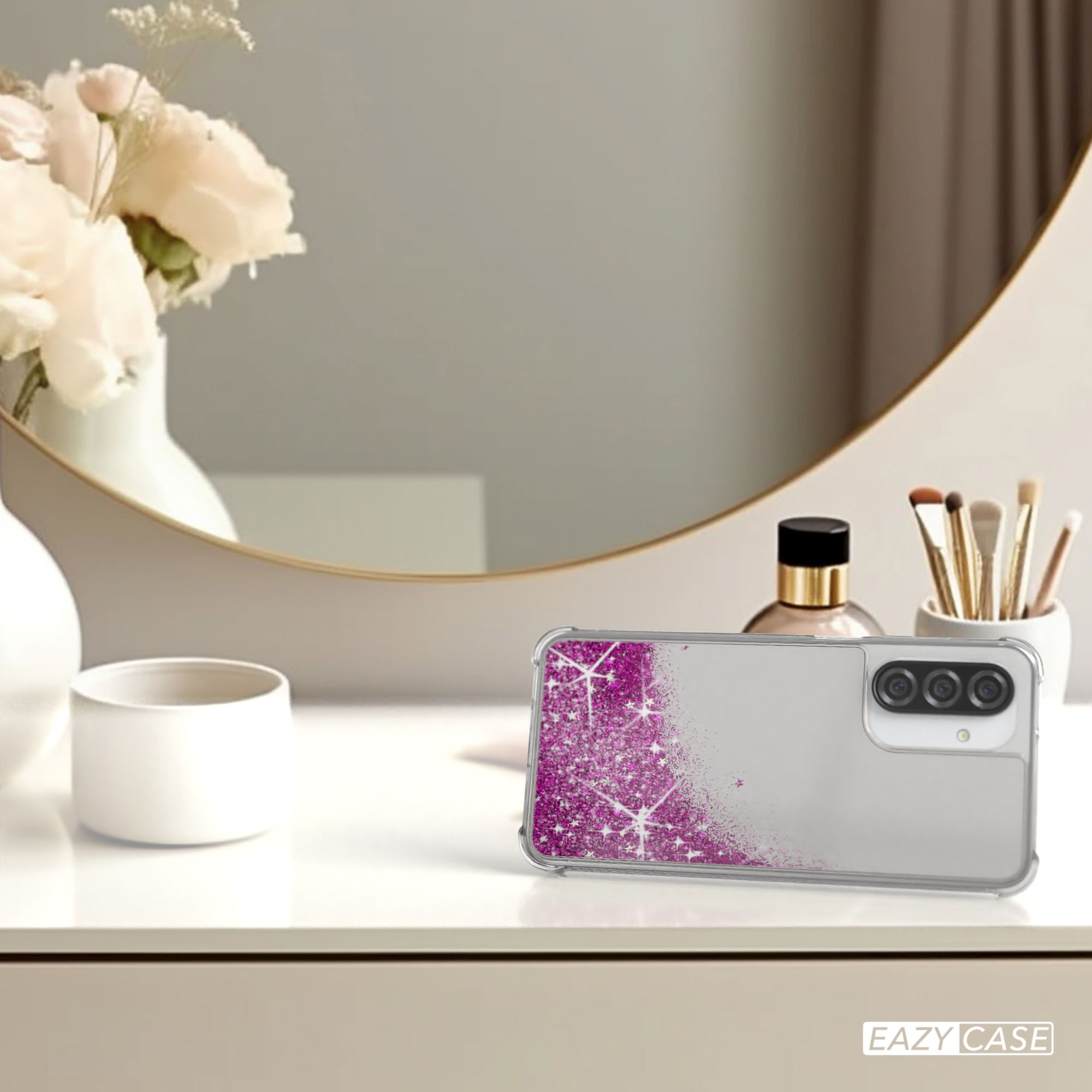 Handyhülle mit Telefon auf einem Schreibtisch. Rosa Glitzerdesign auf der Handyhülle. Zubehör im Hintergrund.