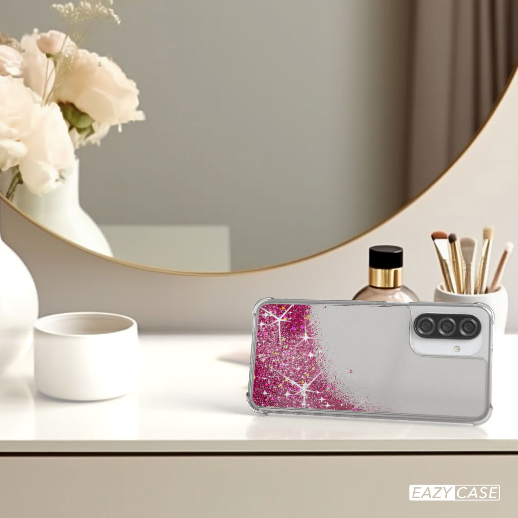 Handyhülle auf Tisch, Spiegel und Vase im Hintergrund. Pinkes Glitzerdesign.
