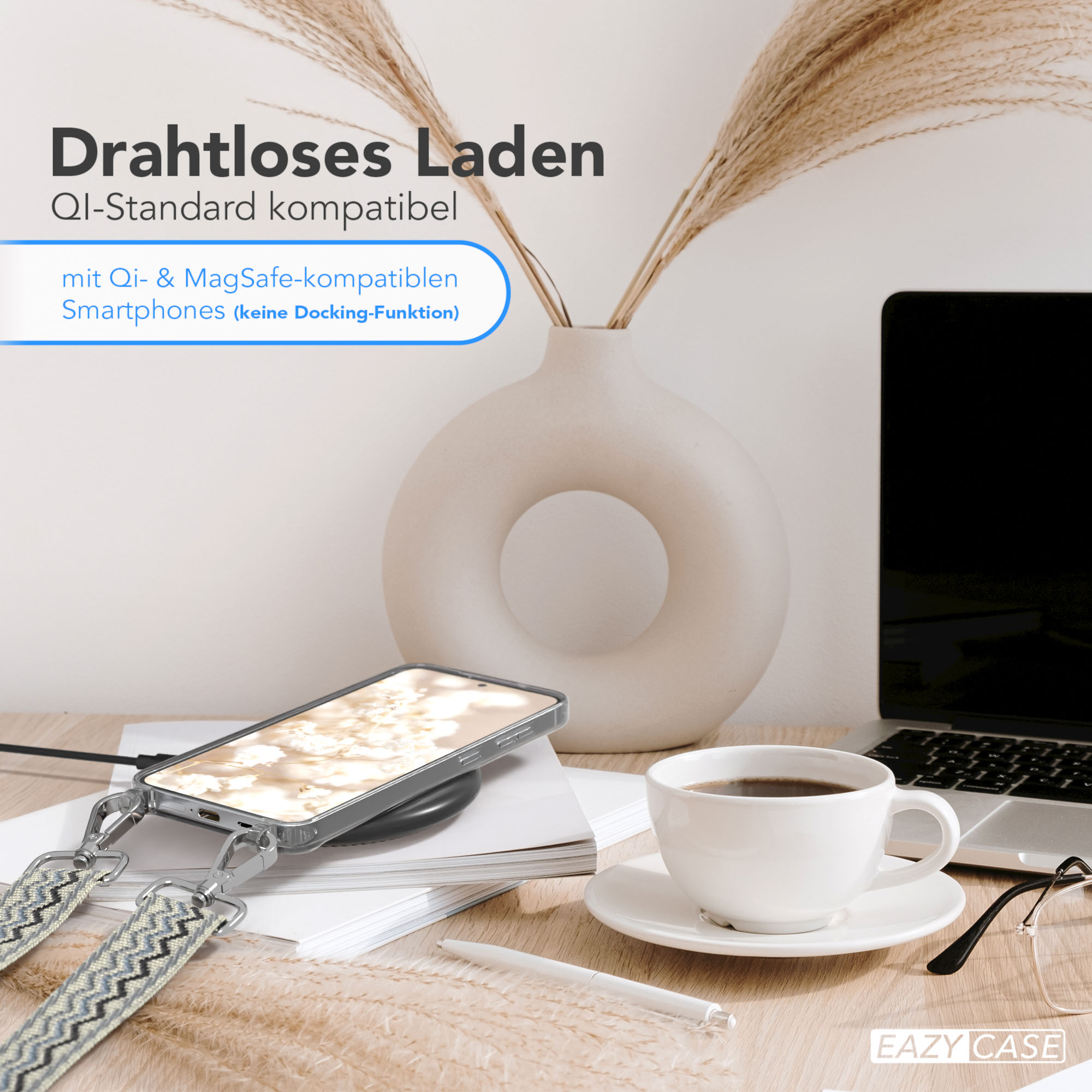 Telefon mit Hülle auf Ladepad, Vase, Kaffee und Brille auf Holztisch.