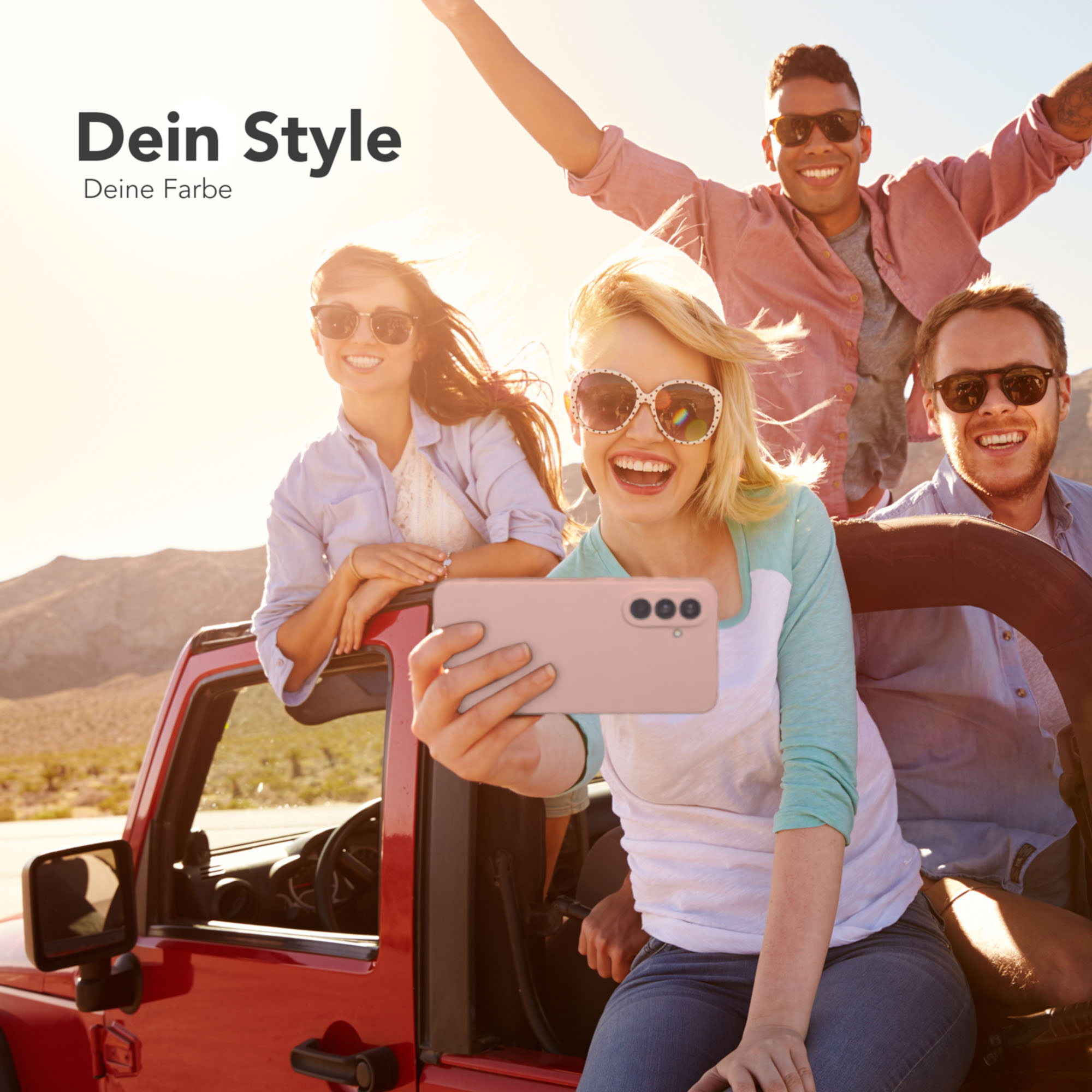 Eine Gruppe von Freunden macht ein Selfie in einem roten Jeep. Der Hintergrund ist eine Wüste.