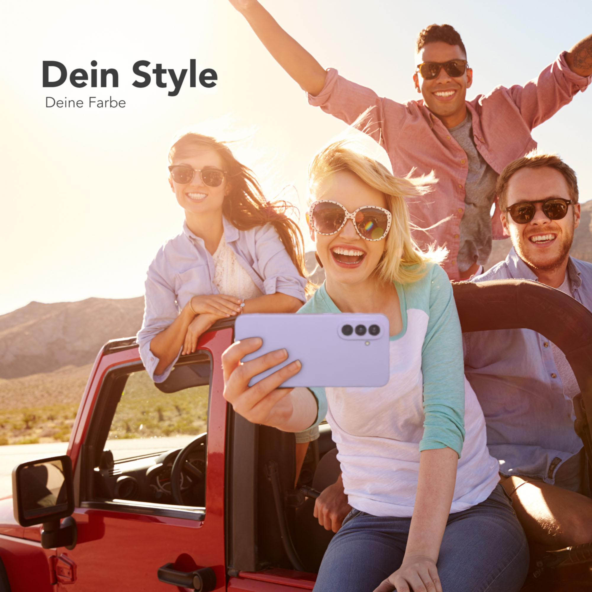 Vier Personen in einem Auto machen ein Selfie mit einer lila Handyhülle, sonnig draußen.