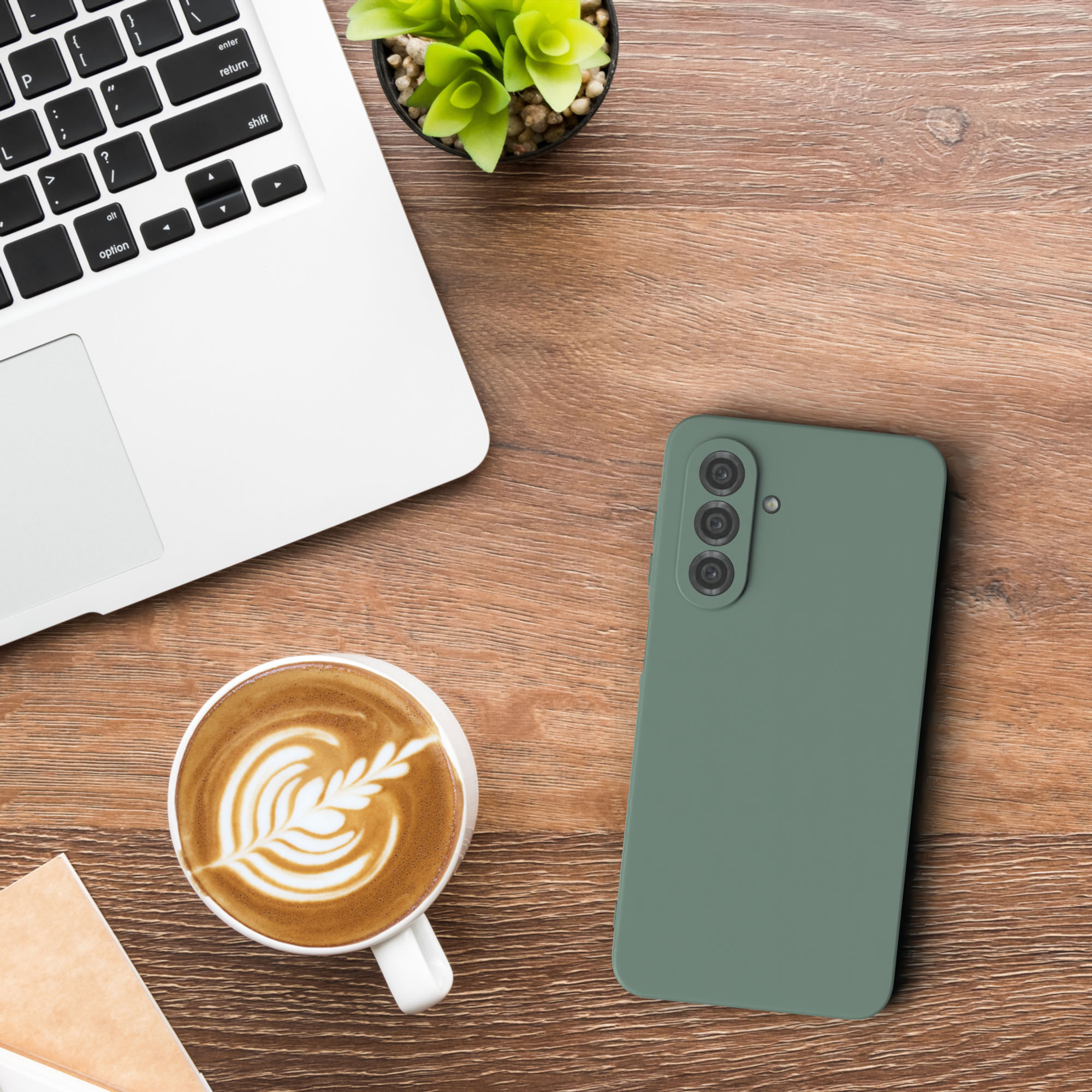 Ein Telefon und eine Kaffeetasse auf einem Holztisch, mit einem Laptop und einem Notizblock in der Nähe.