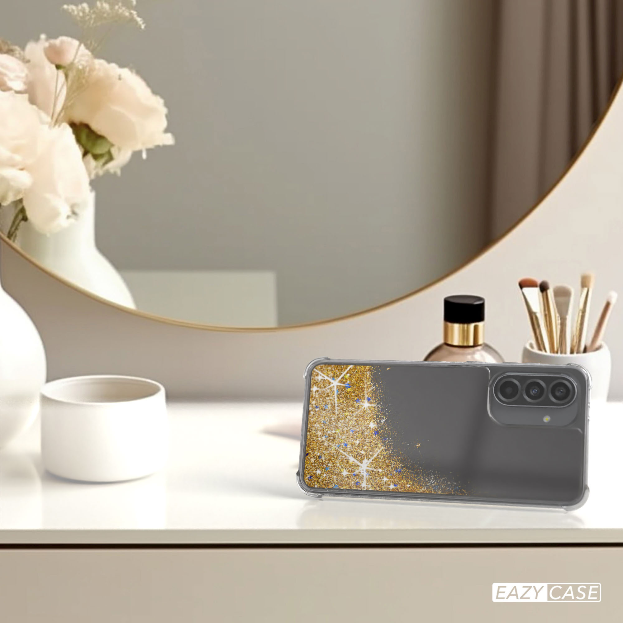 Handyhülle mit Goldglitzer auf Tisch. Blumen in Vase und Spiegel im Hintergrund.