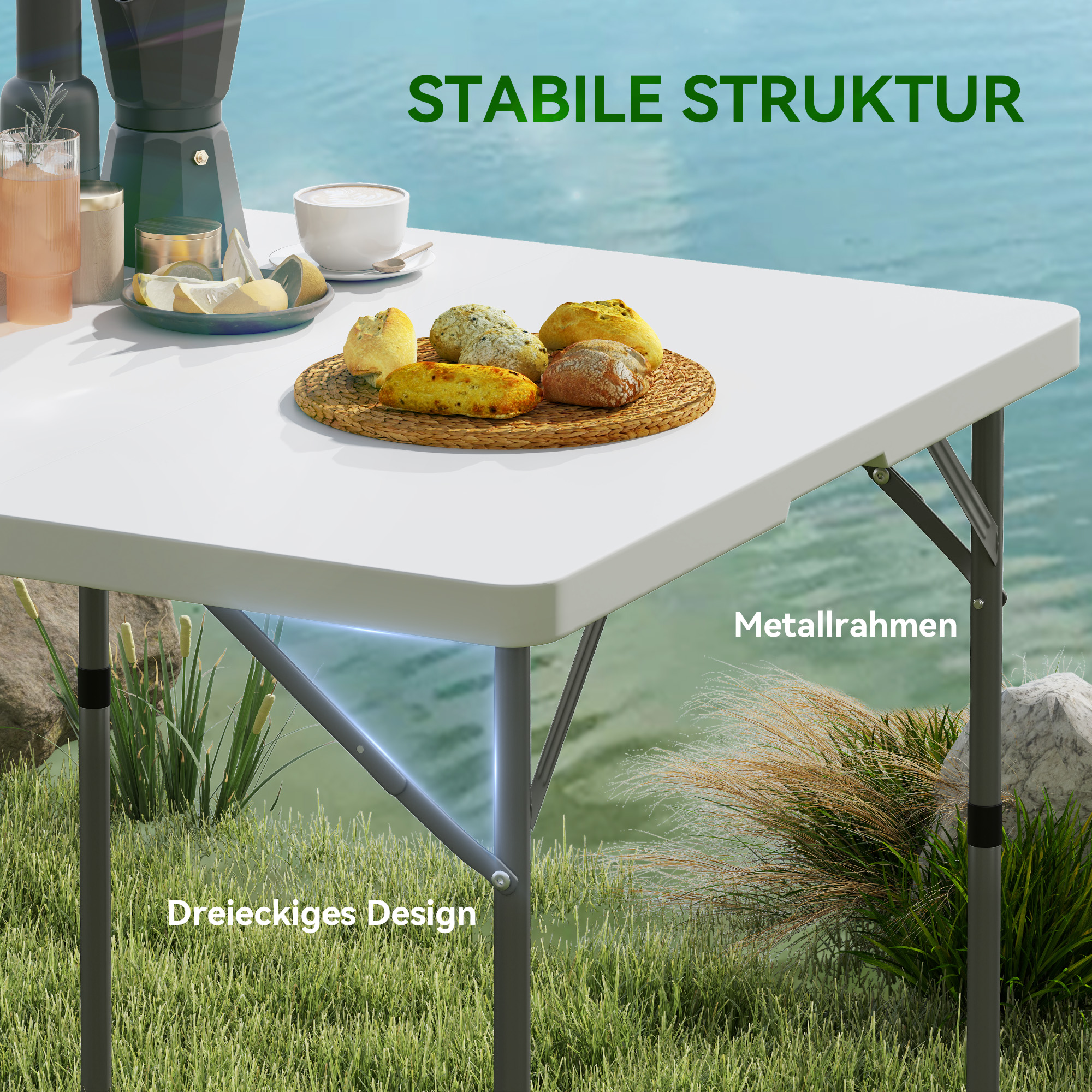 Ein weißer Klapptisch mit Essen darauf, auf grünem Gras stehend. Metallrahmen und dreieckiges Design sind sichtbar.