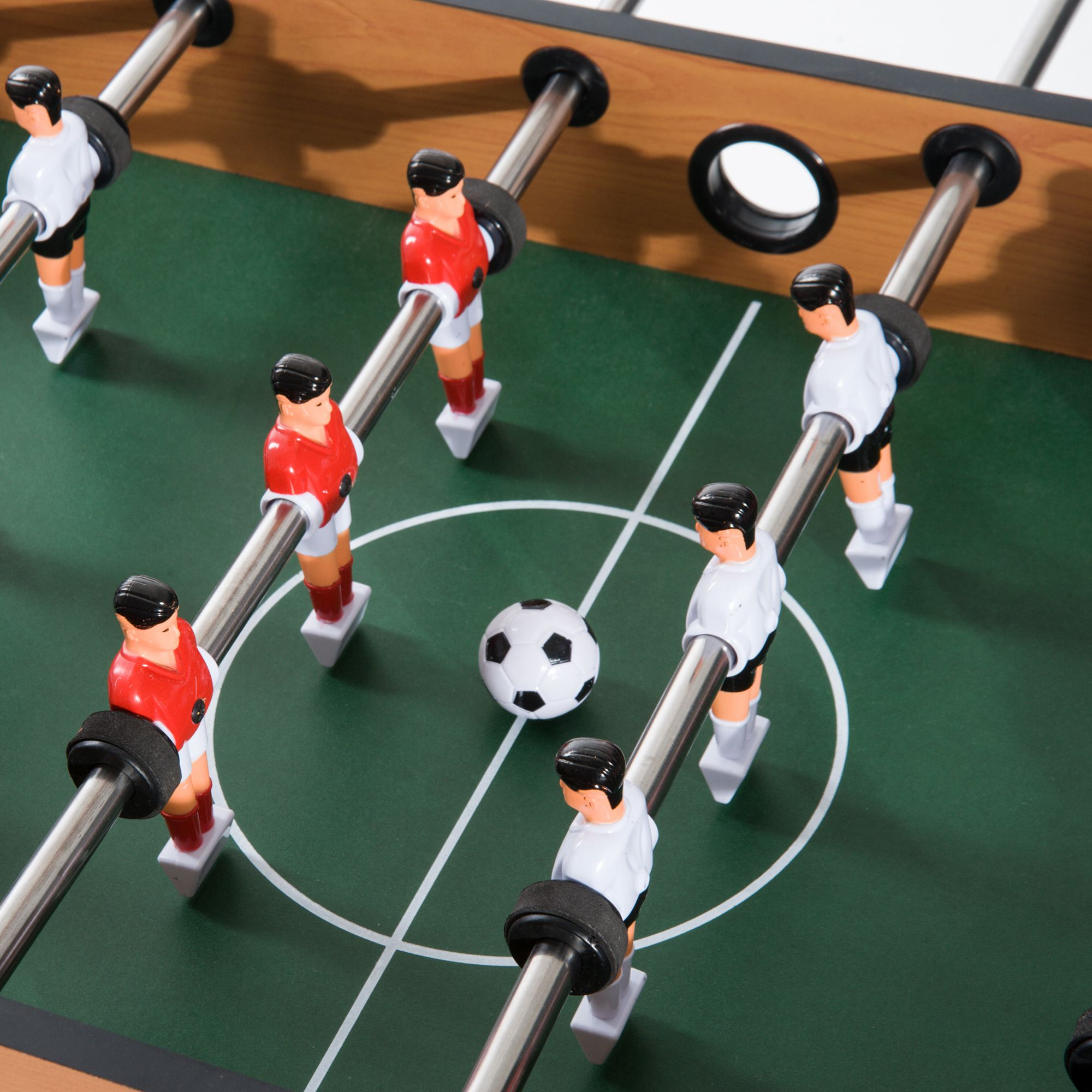 Tischfußballtisch mit Spielern in roten und weißen Uniformen. Ein schwarz-weißer Ball befindet sich in der Mitte.