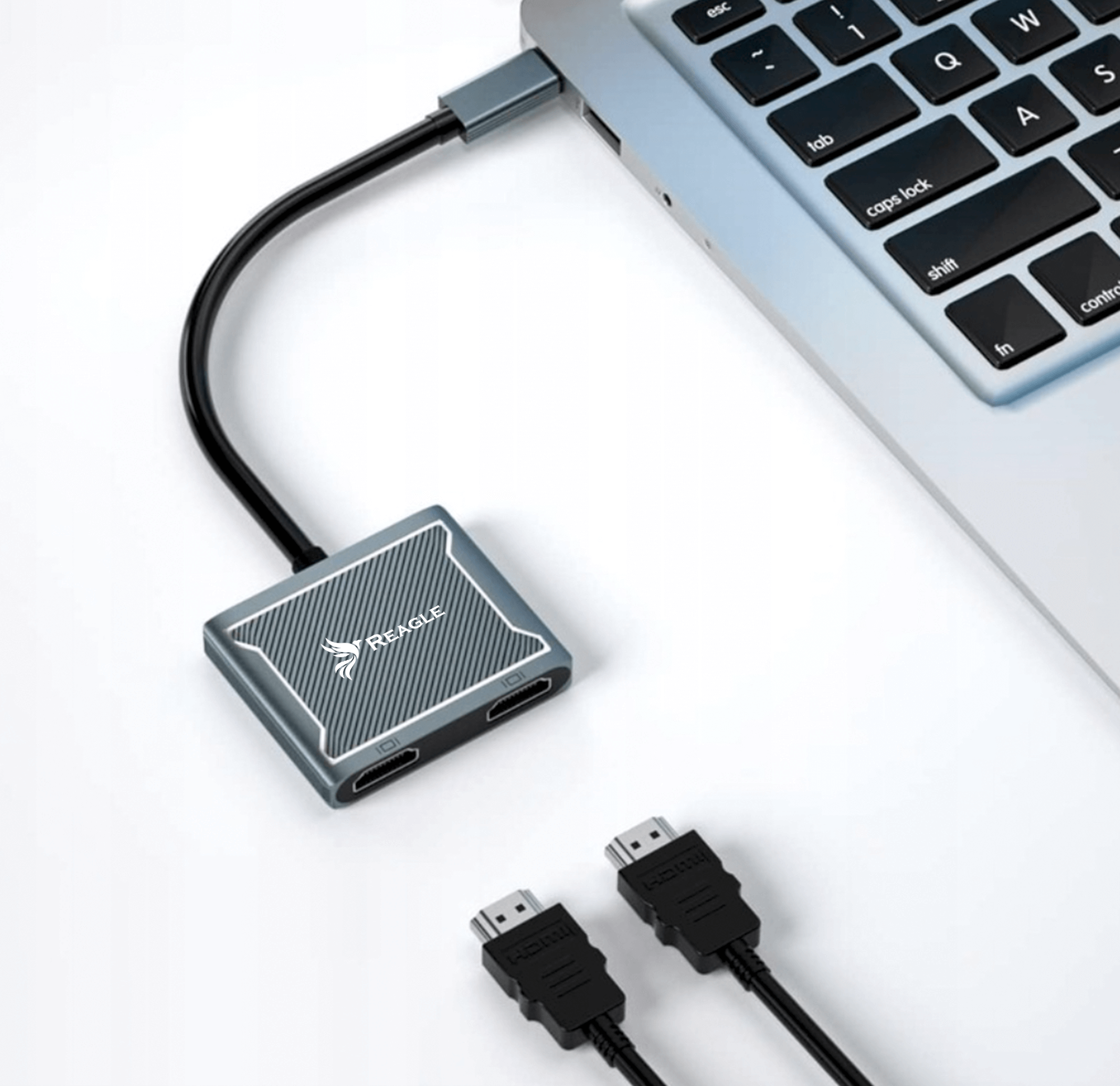 Un adattatore HDMI grigio collegato a un laptop, con due cavi HDMI nelle vicinanze.